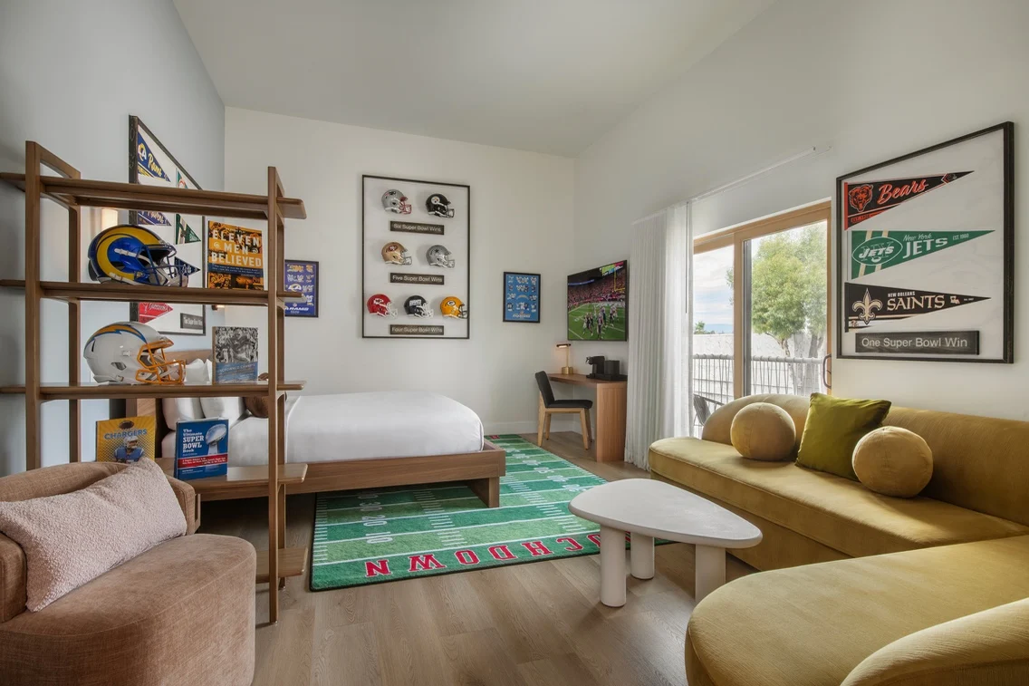 Stylish hotel room featuring a football theme, complete with team memorabilia, a cozy seating area, and a view of the outdoors.
