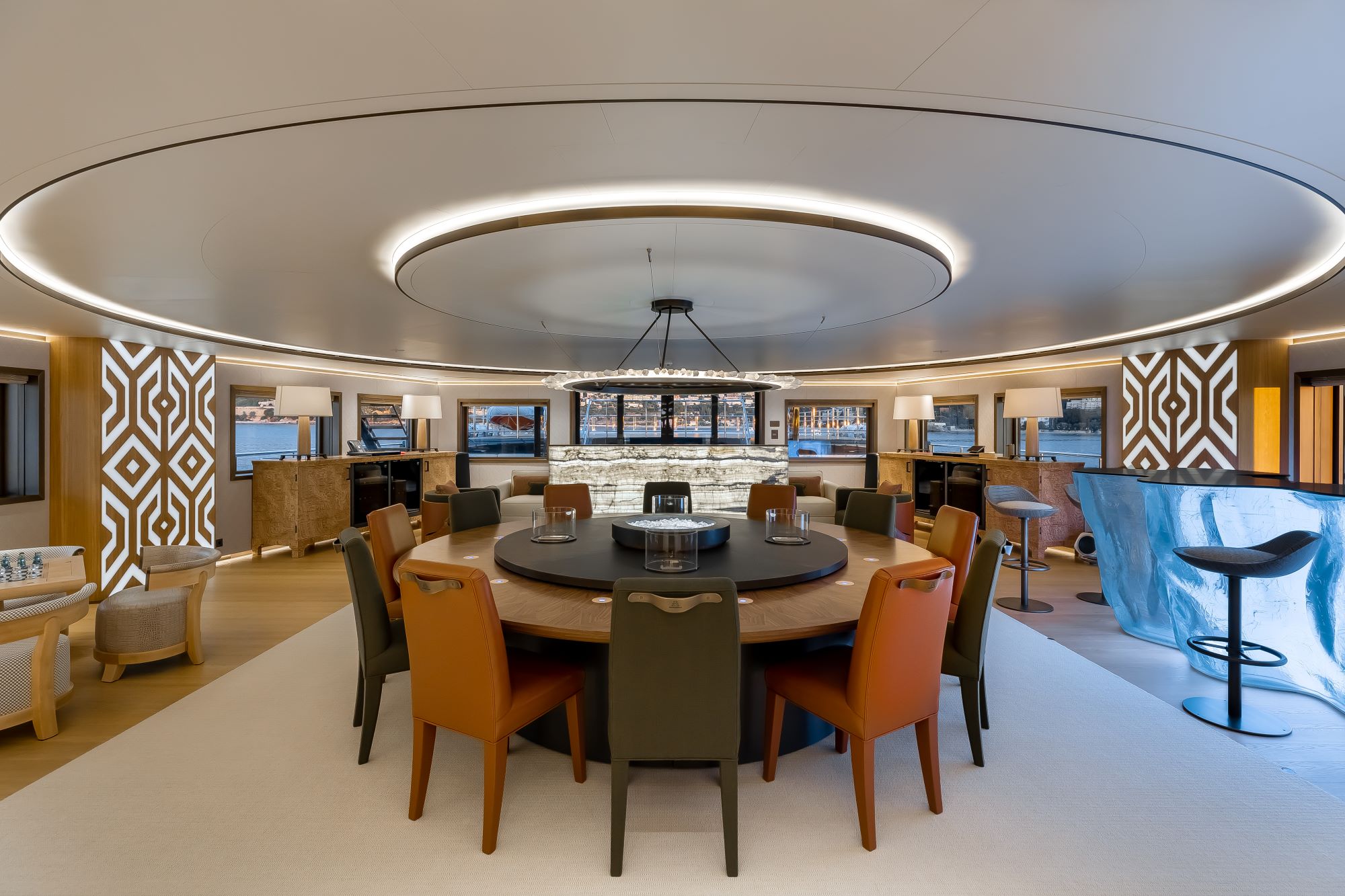Elegant dining area on a luxury yacht, featuring a round table with colorful chairs and stylish decor.