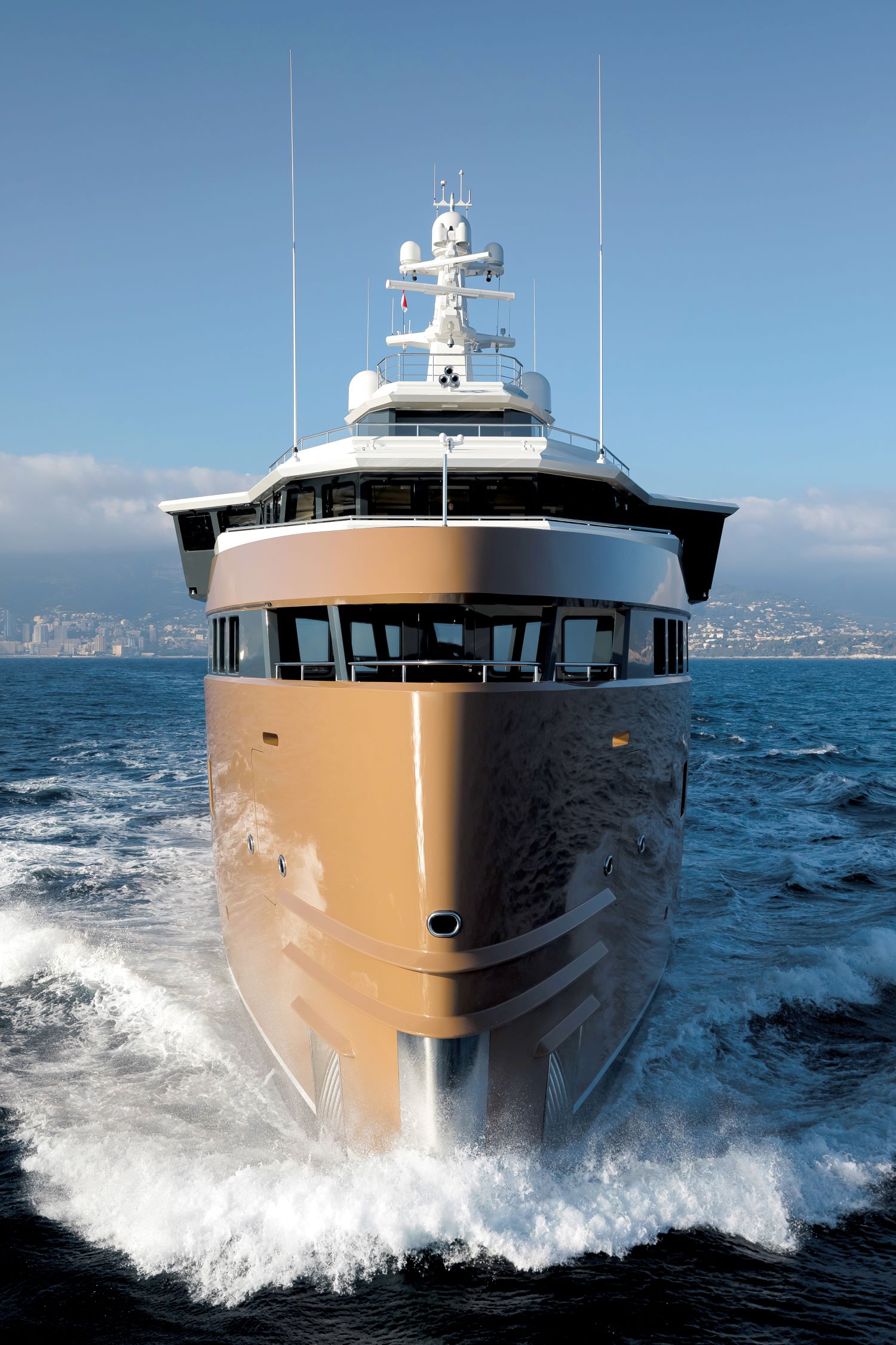 Luxury yacht LA DATCHA cutting through the ocean waves with a clear sky and distant coastline in the background.