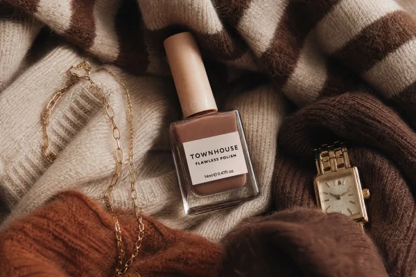 Brown Townhouse nail polish bottle surrounded by cozy knitwear, gold jewelry, and a gold watch. Perfect for winter manicures.