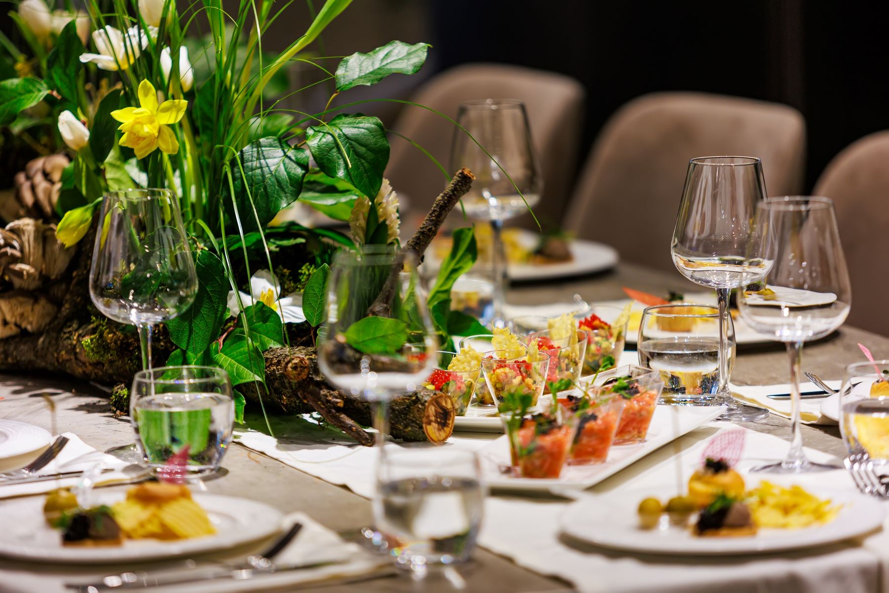 Elegant table setting featuring gourmet dishes, decorative flowers, and wine glasses, perfect for an upscale event.