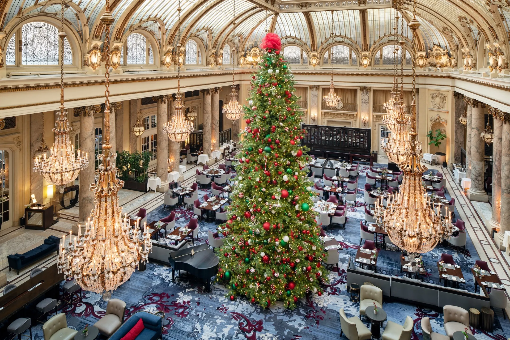 Festively decorated Christmas tree in the Garden Court of the Palace Hotel, with elegant chandeliers and tables set for brunch.