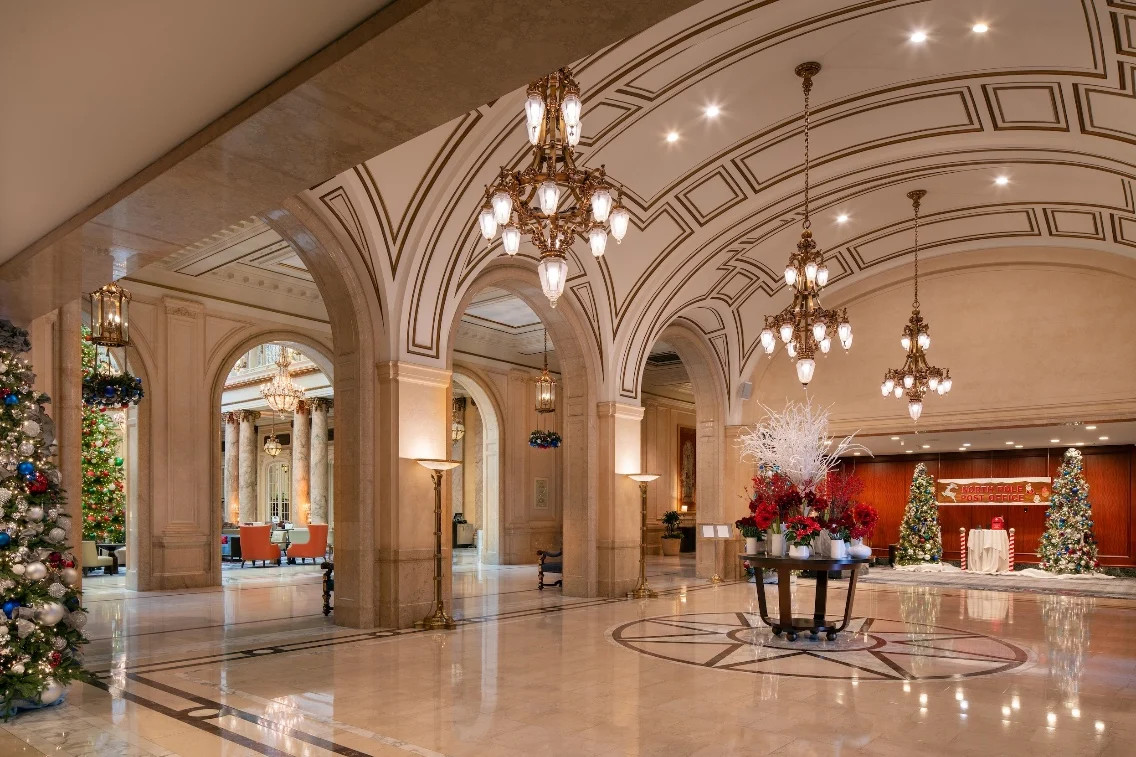 Elegant lobby of the Palace Hotel San Francisco, decorated for the holidays with trees, intricate architecture, and festive displays.