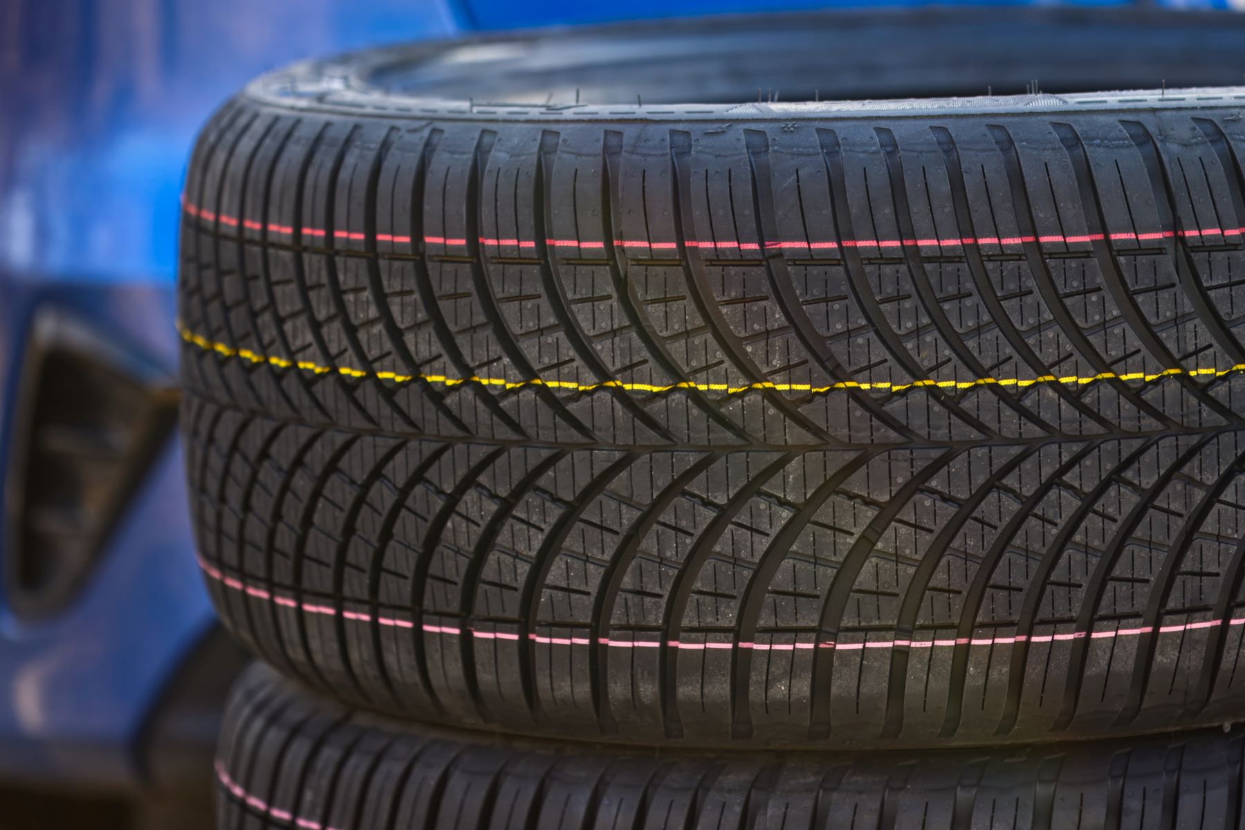 Close-up of all-season tires displaying tread patterns and colored markings, highlighting their durability and performance.