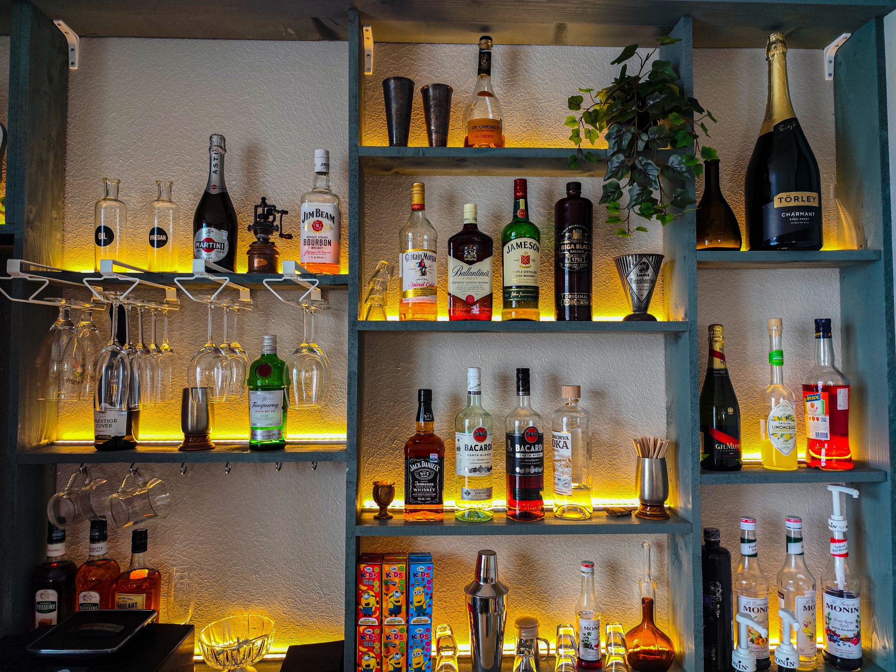 A well-stocked home bar featuring various spirits, cocktail utensils, and glassware, illuminated by warm lighting.