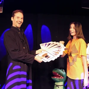 A magician shares a colorful deck of cards with a smiling assistant during a Halloween-themed performance at WonderWorks Orlando.