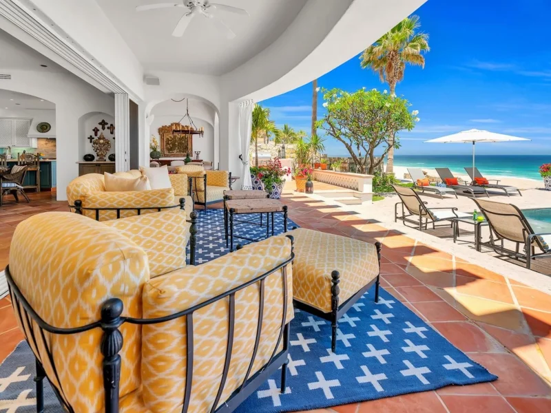Luxurious beachfront patio in Los Cabos, featuring inviting seating, a pool, and ocean views. Perfect for winter getaways.