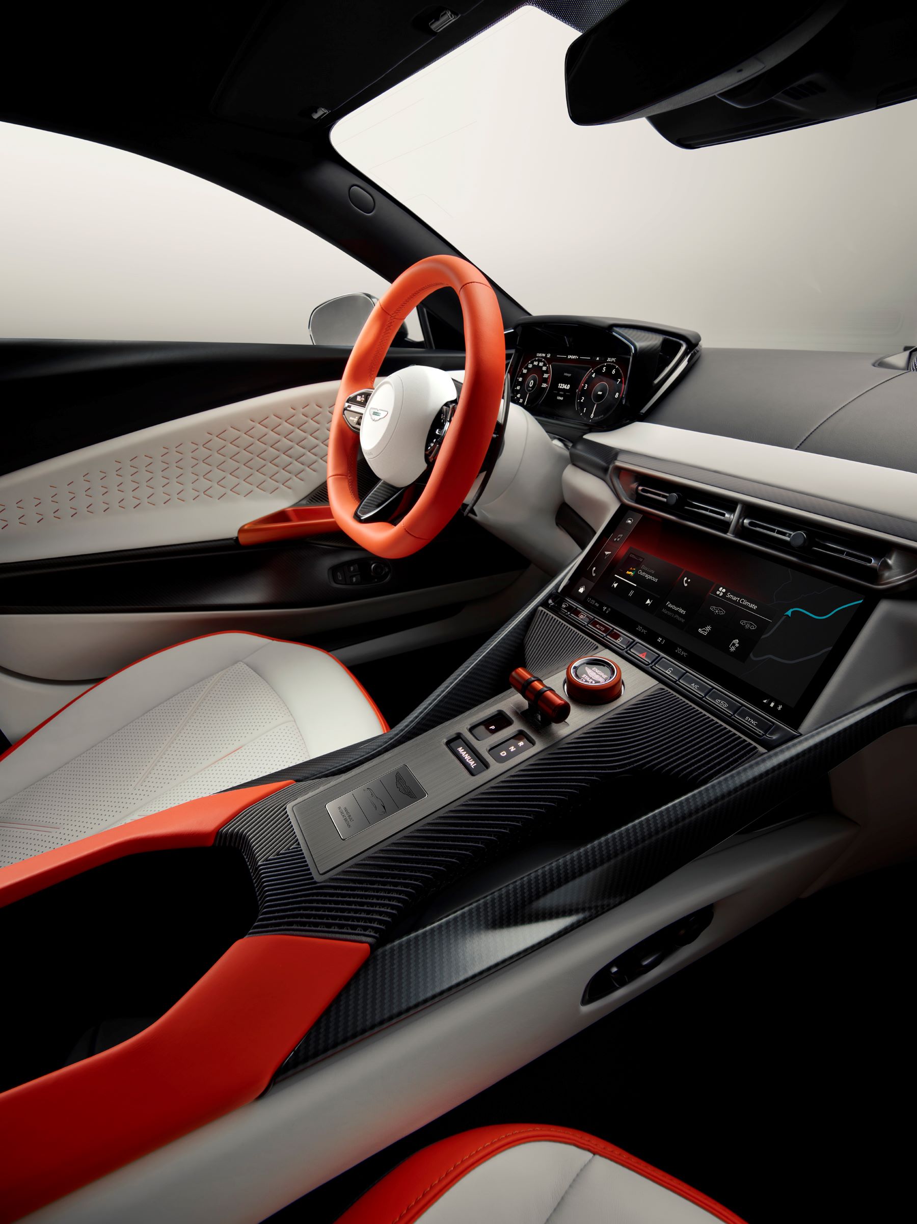 Interior view of the Aston Martin Valen showcasing a sleek design with a modern dashboard, carbon fiber accents, and vibrant red details.