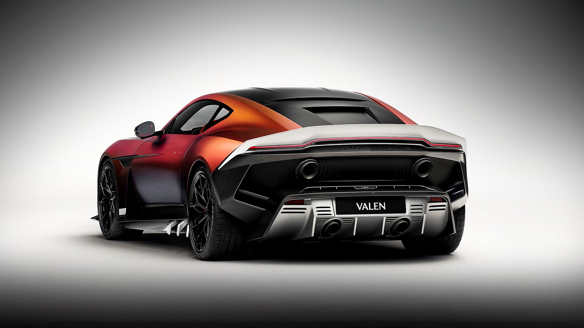 Aston Martin Valen sports car with a striking red and black design, showcasing its powerful rear and modern exhaust features.