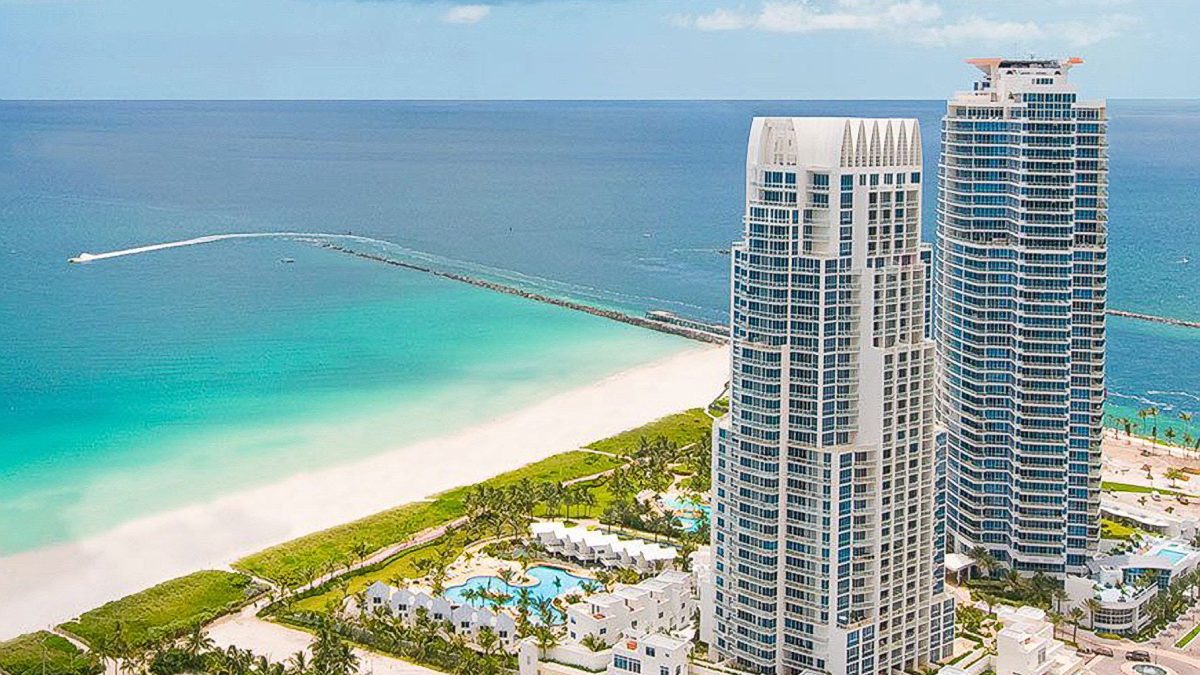 Contemporary high-rise buildings at Continuum in Miami Beach overlooking the turquoise ocean and sandy shoreline.