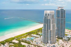 Contemporary high-rise buildings at Continuum in Miami Beach overlooking the turquoise ocean and sandy shoreline.