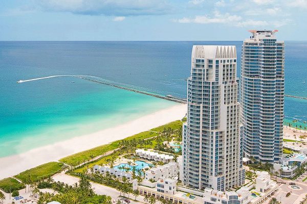 Contemporary high-rise buildings at Continuum in Miami Beach overlooking the turquoise ocean and sandy shoreline.