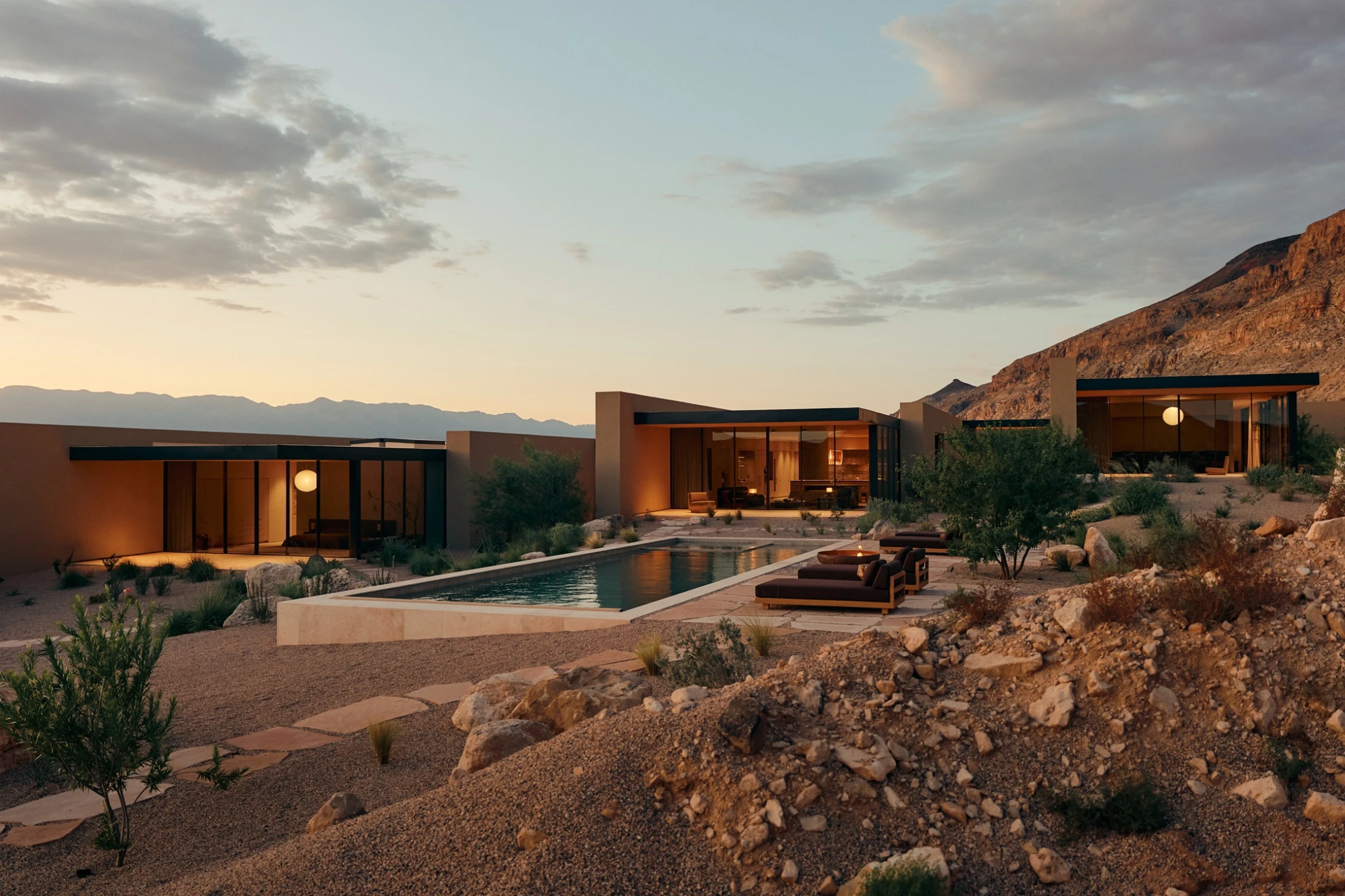 A modern retreat with large windows and a pool, surrounded by desert landscape and mountains at sunset in Southern Utah.