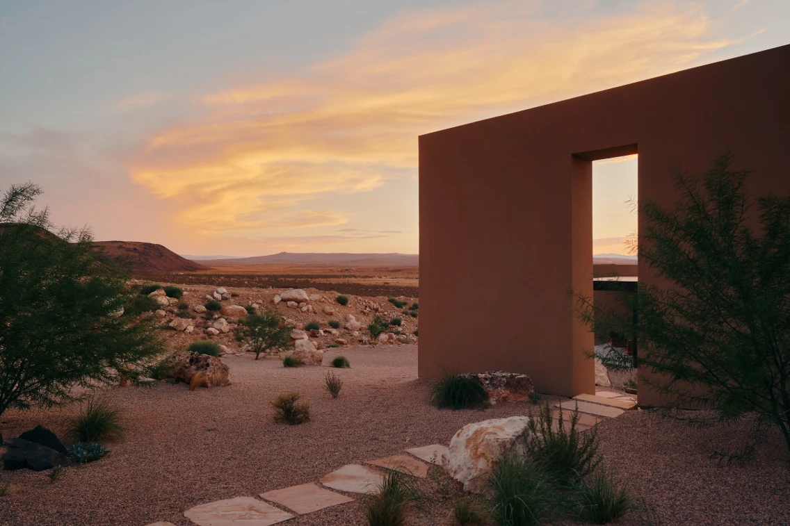 Sculptural retreat in southern Utah blending with desert landscape at sunset, framed by minimalist architecture and natural elements.