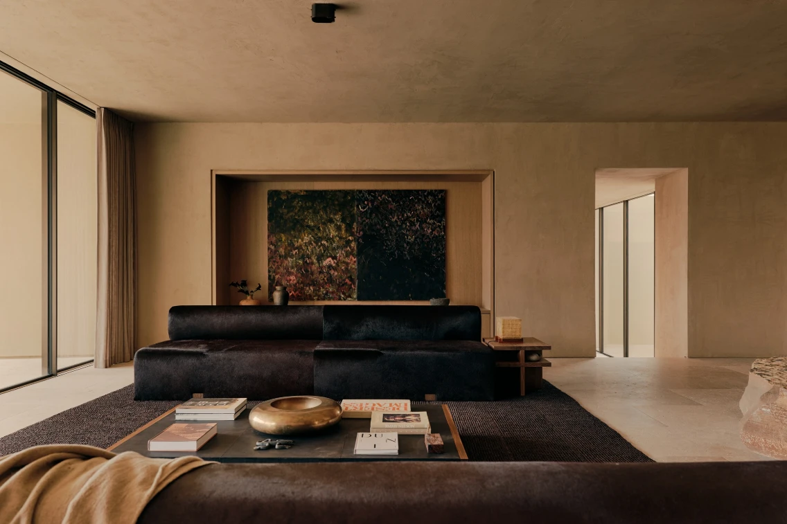 Stylish living space featuring dark sofas, a low coffee table with books, and large windows that invite natural light.