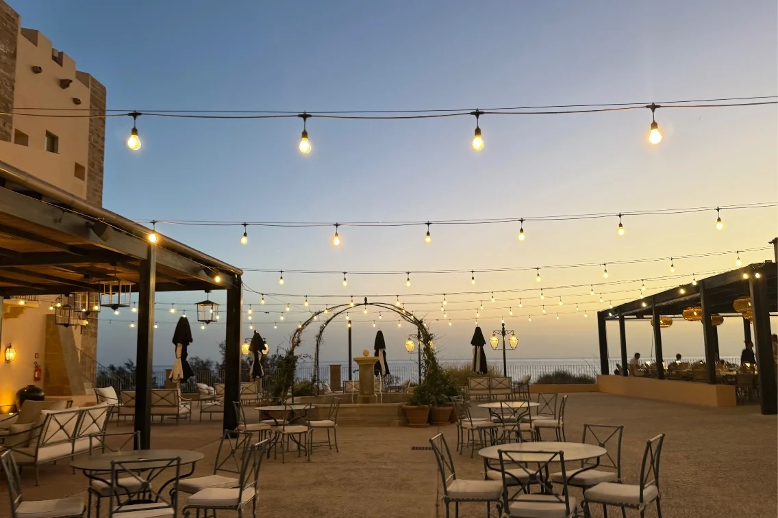 Elegant outdoor dining setup with string lights and a sunset view at Rocco Forte's Verdura Resort.