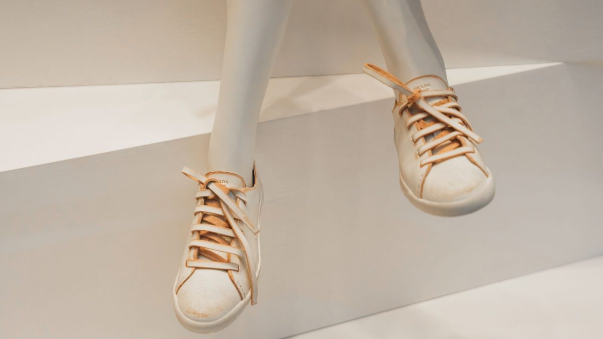 Distressed sneakers displayed on a mannequin, featuring a white leather exterior and beige laces, embodying the distressed-luxe trend.