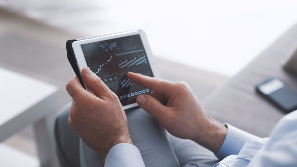 A person analyzing cryptocurrency market trends on a tablet, with graphs and data displayed on the screen.