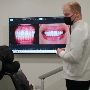 Dental professional discussing before-and-after images of dental treatments during a consultation with a patient.