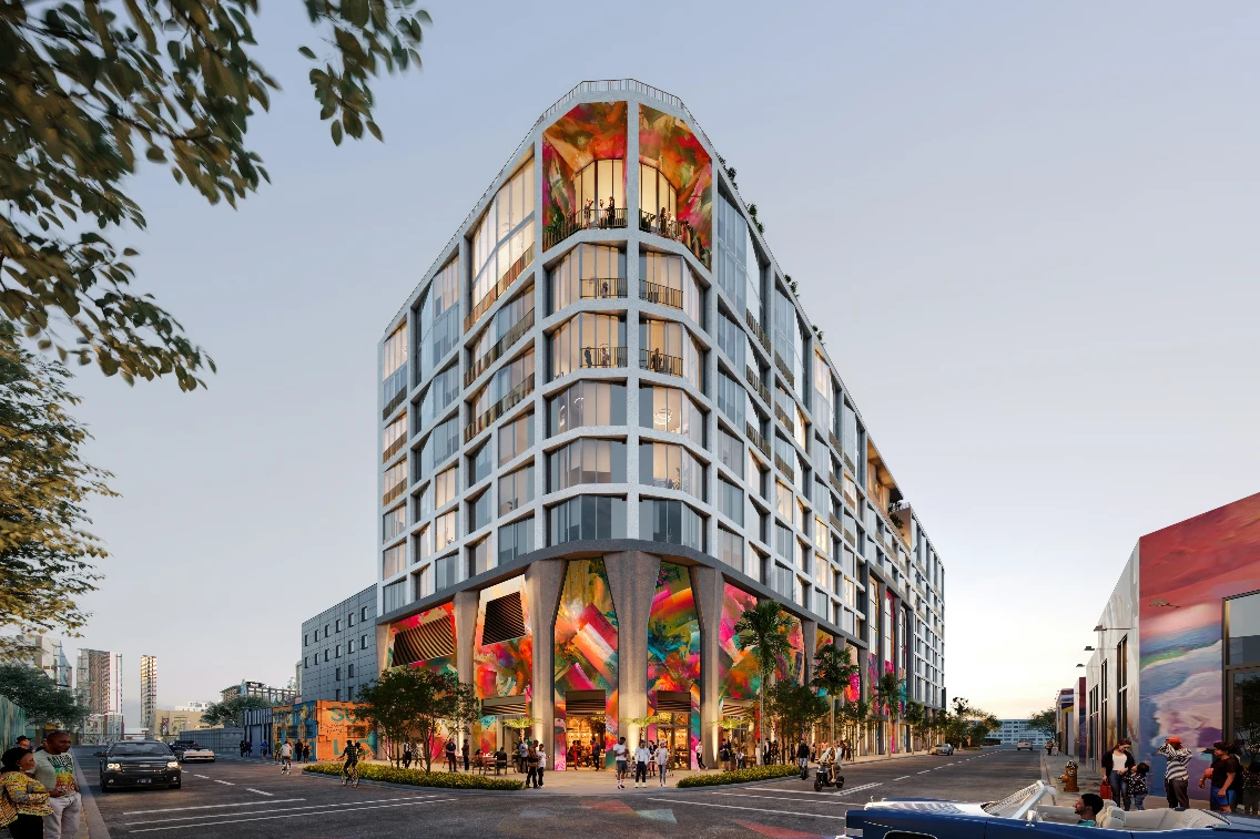 Modern multi-story building with vibrant murals and street activity in an urban Miami setting.