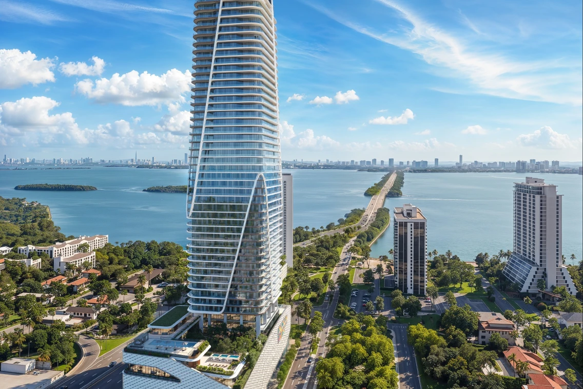 Aerial view of Miami showing a modern skyscraper along the waterfront with lush greenery and city skyline in the background.