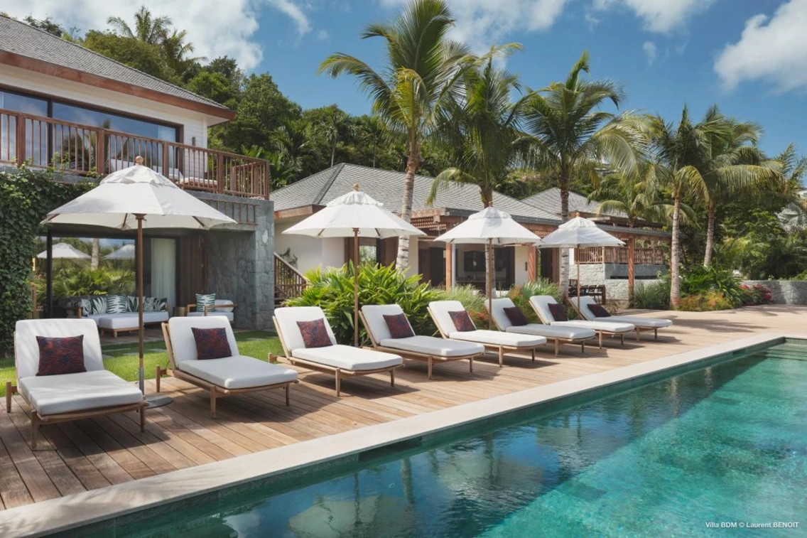 Luxurious villa with sun loungers, umbrellas, and lush tropical surroundings by a sparkling pool in St. Barts.