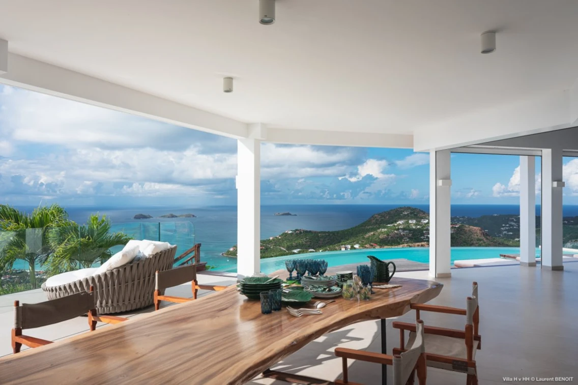 Spacious outdoor dining area with panoramic ocean views and modern furnishings overlooking St. Barts' scenic coastline.