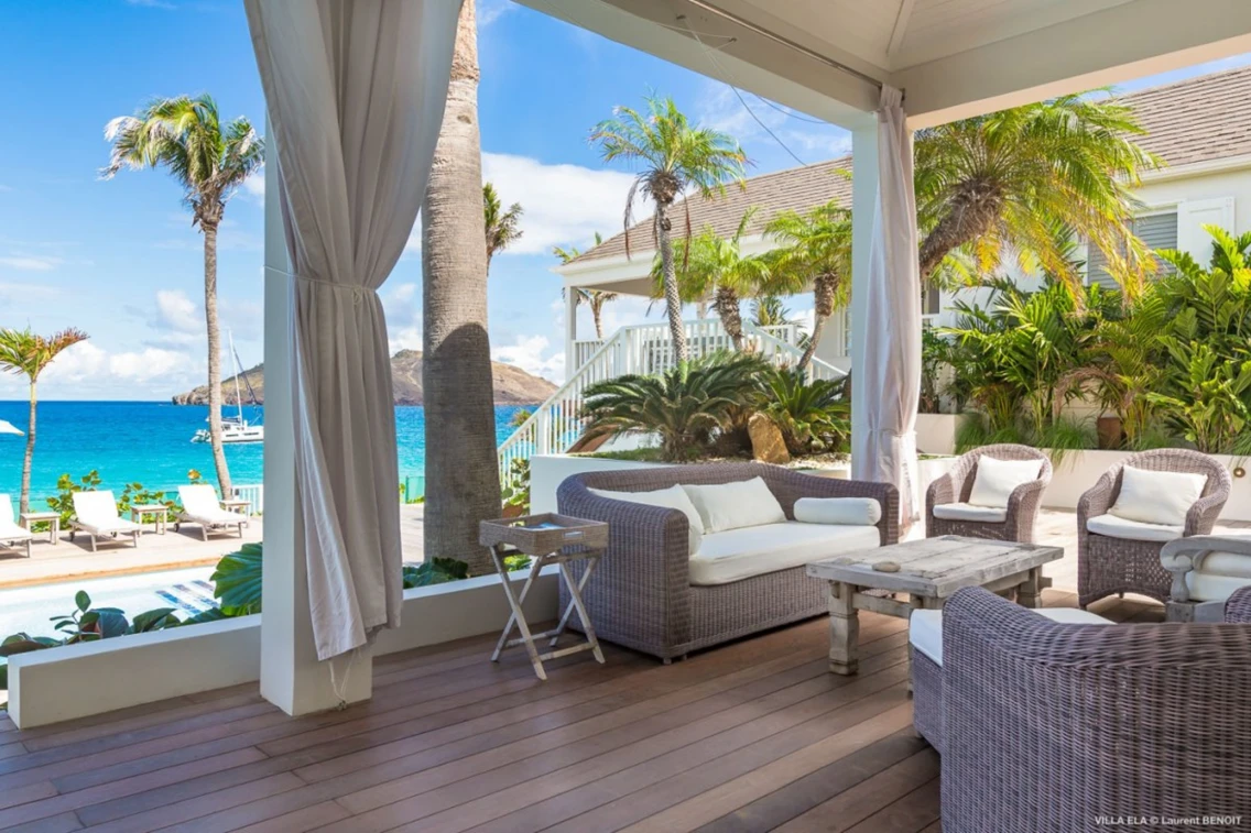 Seaside terrace with comfortable seating and tropical landscaping, showcasing the stunning blue waters of St. Barts.