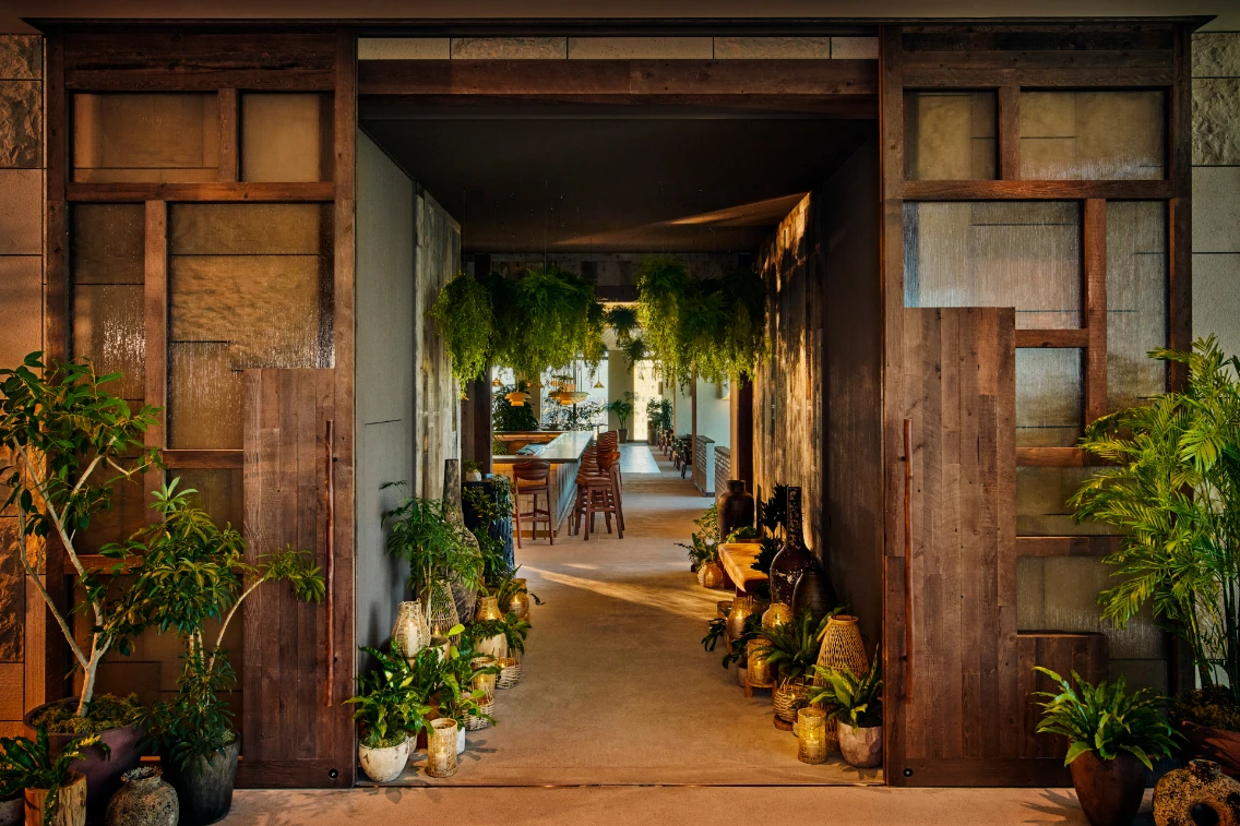 Entrance to 1 Hotel Tokyo features a warm wooden design surrounded by lush greenery, creating a natural ambiance.