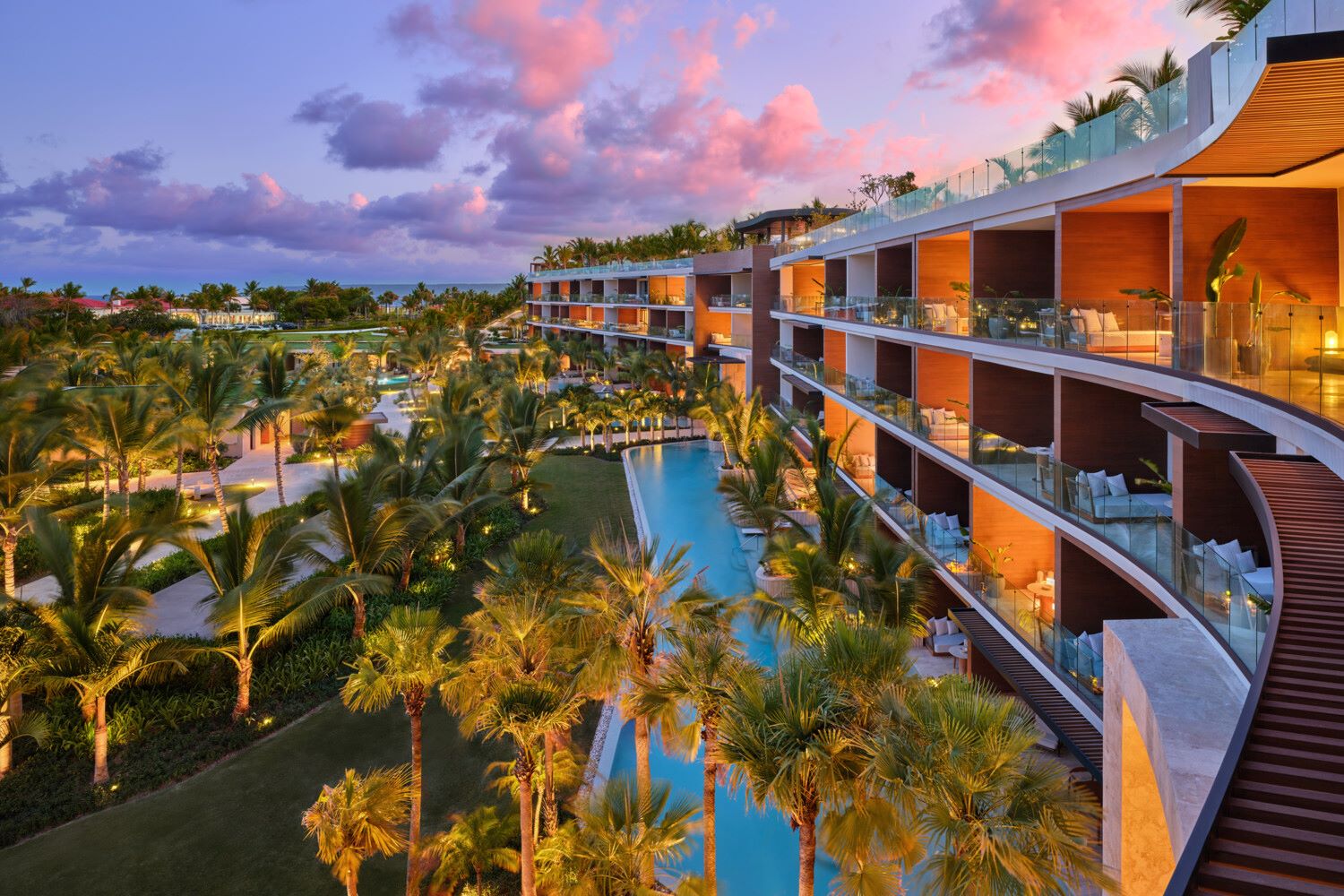 Luxurious resort exterior at sunset with palm trees, pool, and modern architecture at The St. Regis Cap Cana.