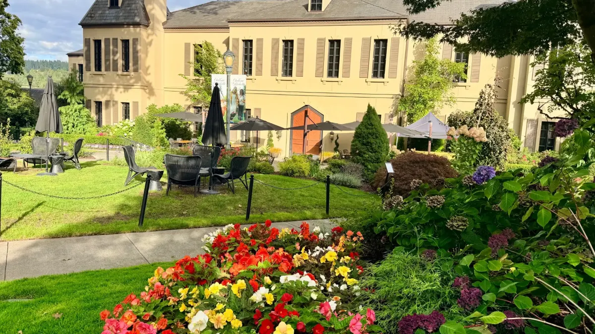 Colorful flower beds in the foreground with outdoor seating and the Chateau Ste. Michelle building in the background.