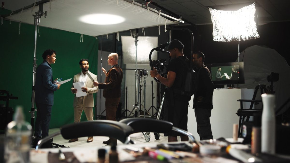 A group of men collaborates on a creative project in a studio setting with cameras and lighting equipment.