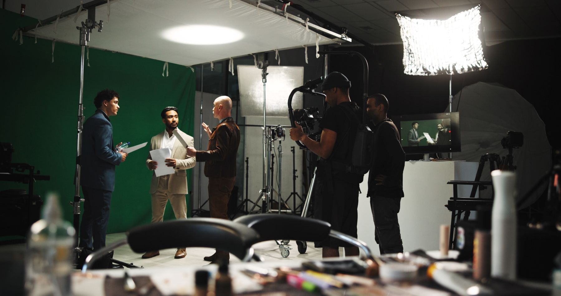 A group of men collaborates on a creative project in a studio setting with cameras and lighting equipment.