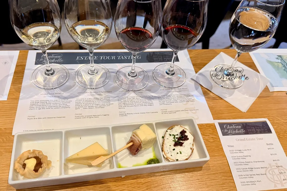 Wine tasting setup with four glasses of wine and a plate of assorted cheeses and accompaniments at Chateau Ste. Michelle.