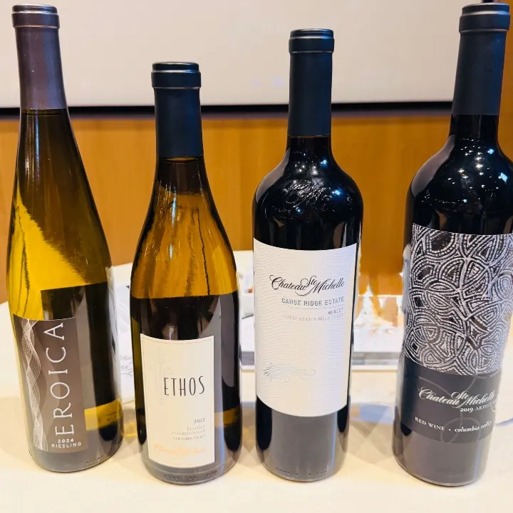 Four wine bottles from Chateau Ste. Michelle, including Riesling and Merlot varieties, displayed on a tasting table.