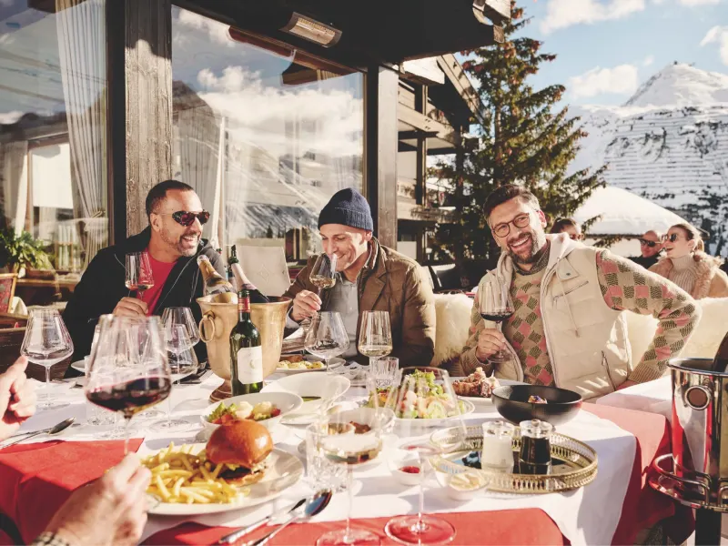 Friends enjoy a luxurious breakfast outdoors with mountain views, featuring gourmet dishes and fine wines.