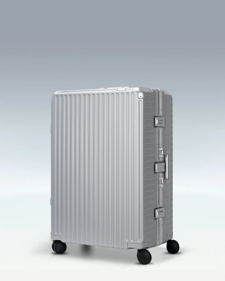 Silver hard-shell suitcase with a ribbed design and wheels, ideal for fall travel.