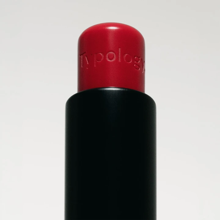 Berry red lip balm with a sleek black tube, perfect for fall beauty looks.