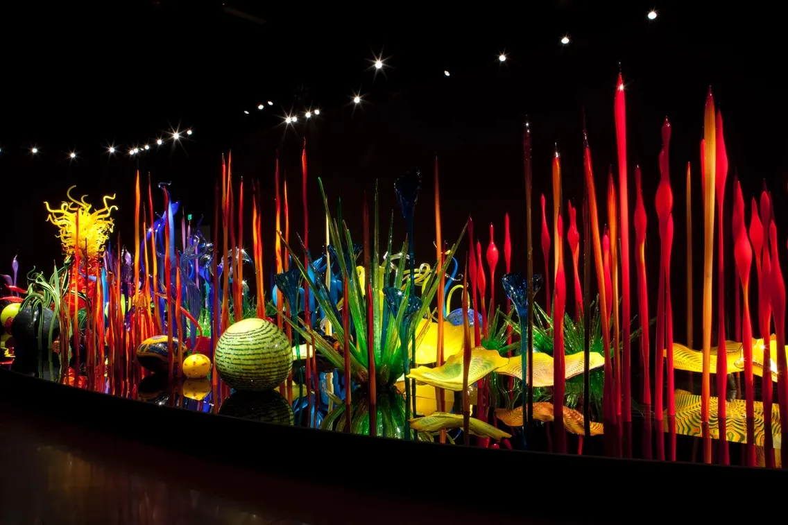Colorful glass sculptures illuminated in a dark space, showcasing vibrant forms and textures at Chihuly Garden and Glass.