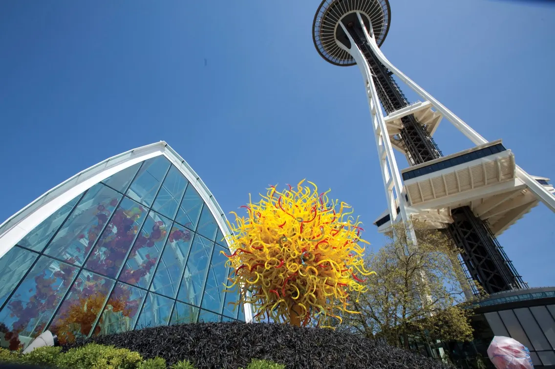 Chihuly Garden and Glass features a vibrant yellow glass sculpture with the Space Needle in the background against a clear blue sky.