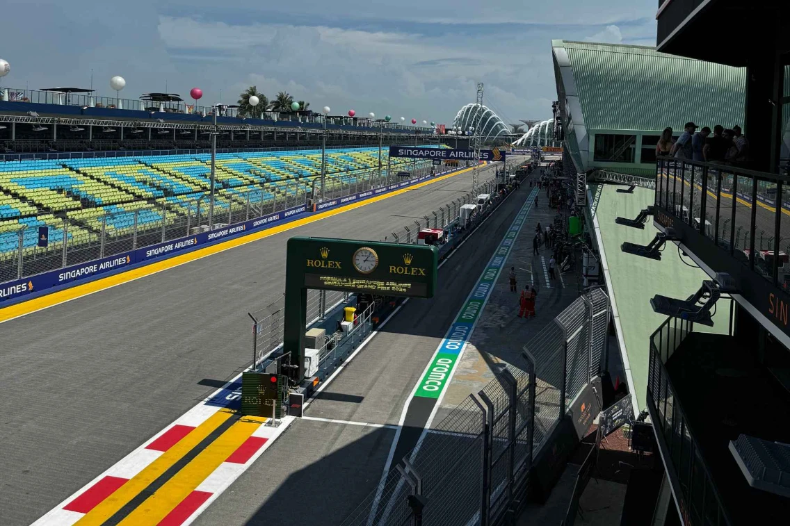 View of the racing circuit with grandstands, pit lane, and a Rolex clock at the Singapore Grand Prix venue.