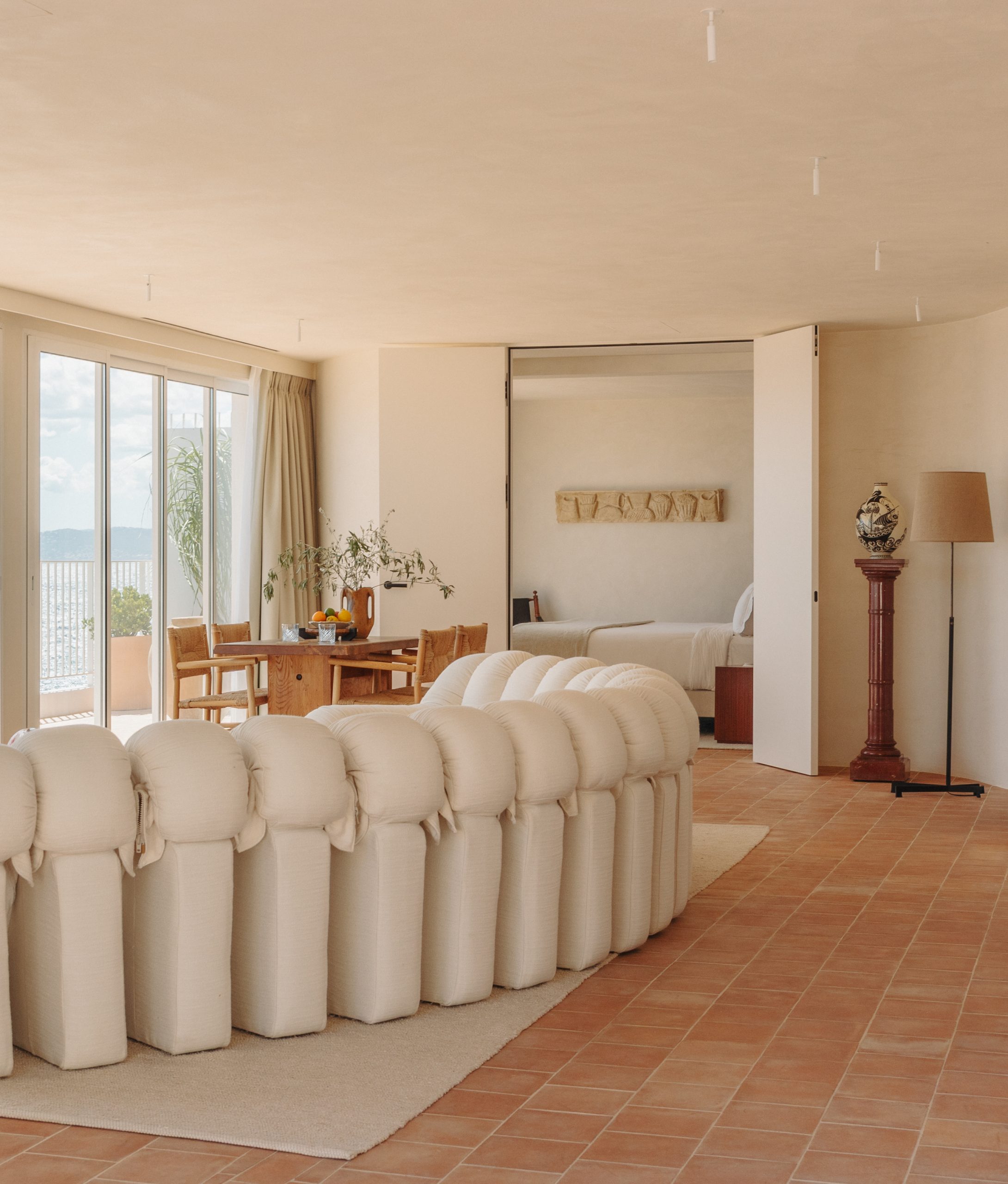 Spacious and stylish lounge area featuring a plush sofa, wooden dining table, and stunning views of the Mediterranean.