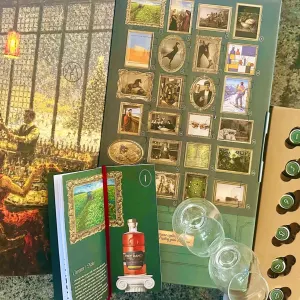 A whiskey tasting gift set featuring glasses, a guidebook, and illustrated cards displayed on a textured surface.