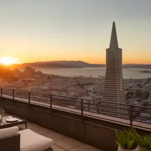 Sunset view of San Francisco skyline featuring the Transamerica Pyramid and Alcatraz Island from a hotel balcony.
