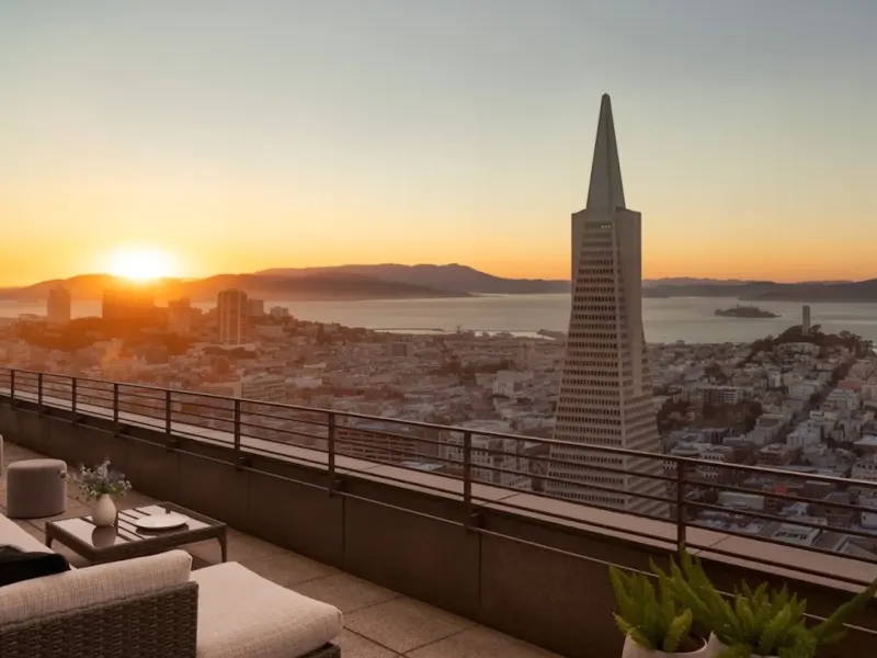 Sunset view of San Francisco skyline featuring the Transamerica Pyramid and Alcatraz Island from a hotel balcony.