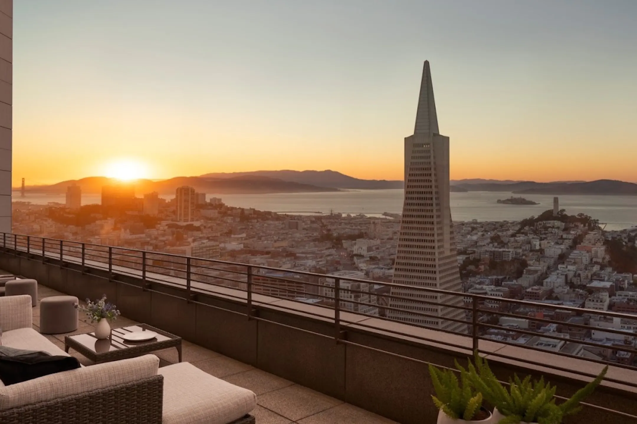 Sunset view of San Francisco skyline featuring the Transamerica Pyramid and Alcatraz Island from a hotel balcony.