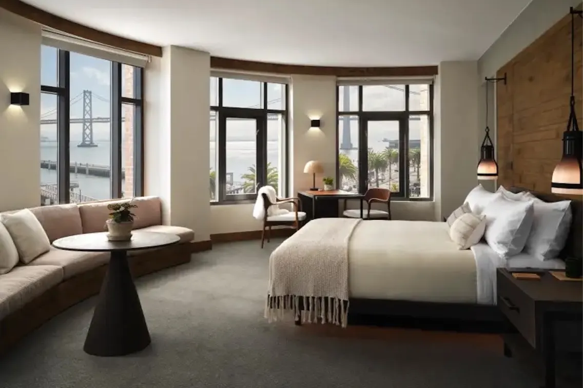 Panoramic suite in a San Francisco hotel featuring large windows, modern decor, and a view of the waterfront.