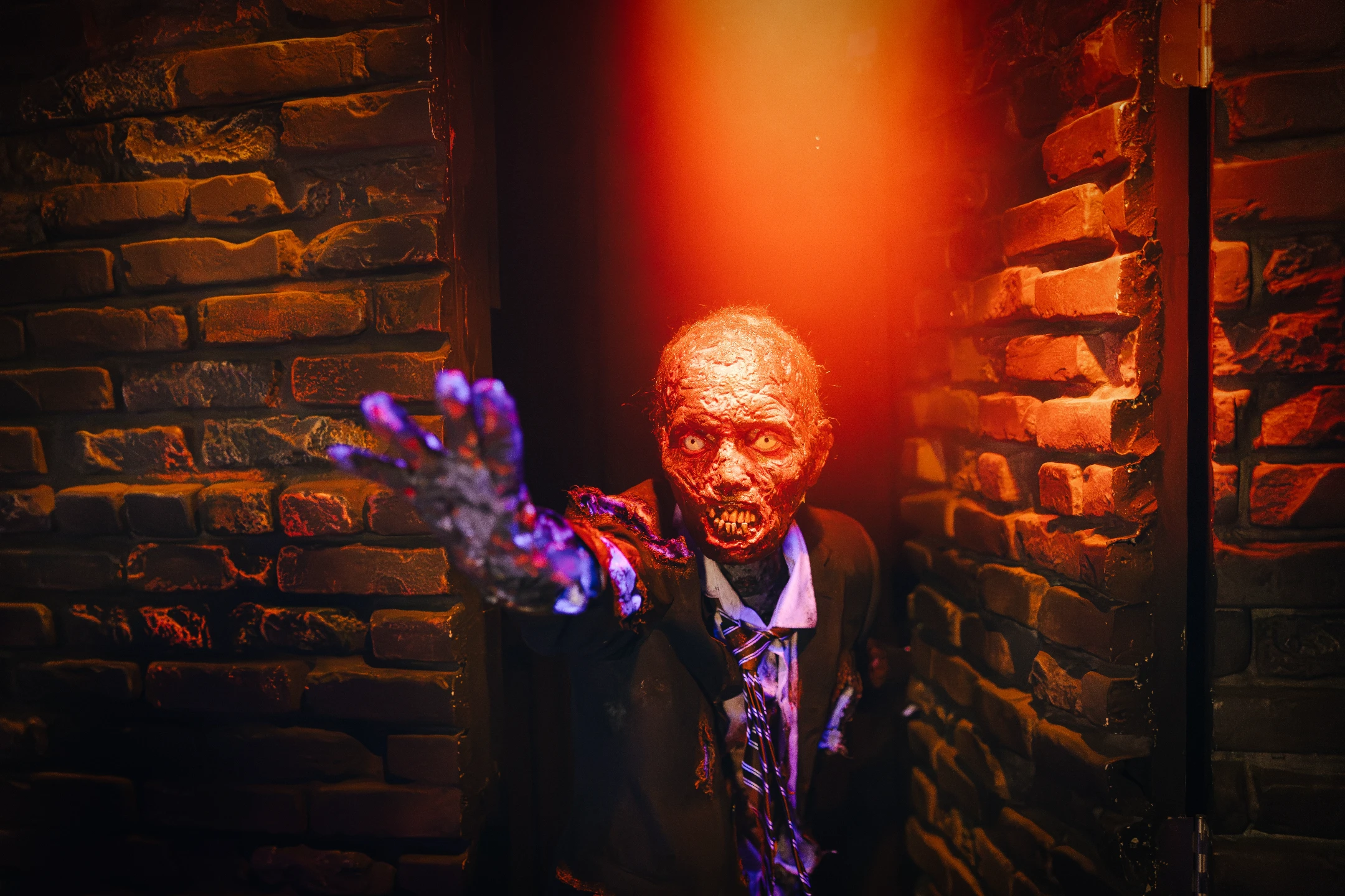 A zombie figure reaching out with a sinister expression against a dimly lit brick wall, perfect for Halloween themes.