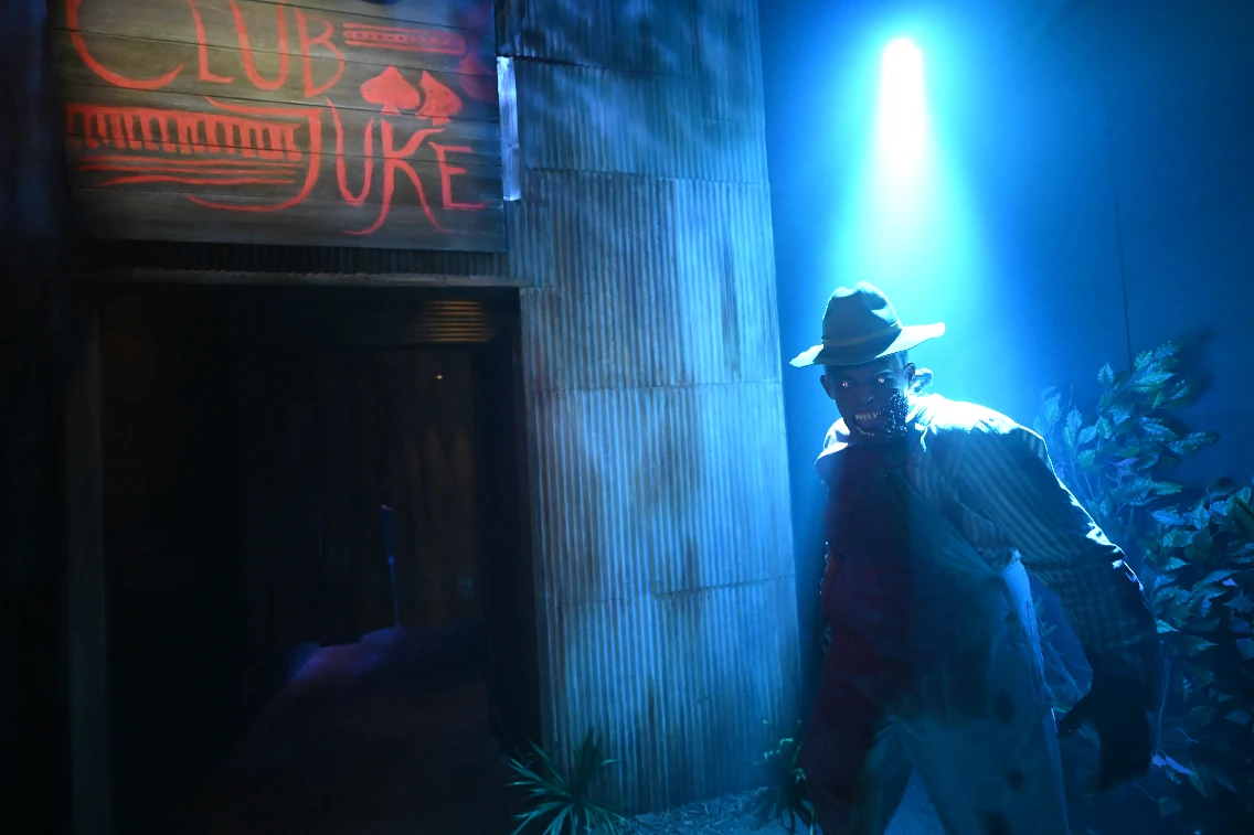 A spooky monster stands outside a dimly lit venue called Club Juke, with blue lighting accentuating the eerie atmosphere.