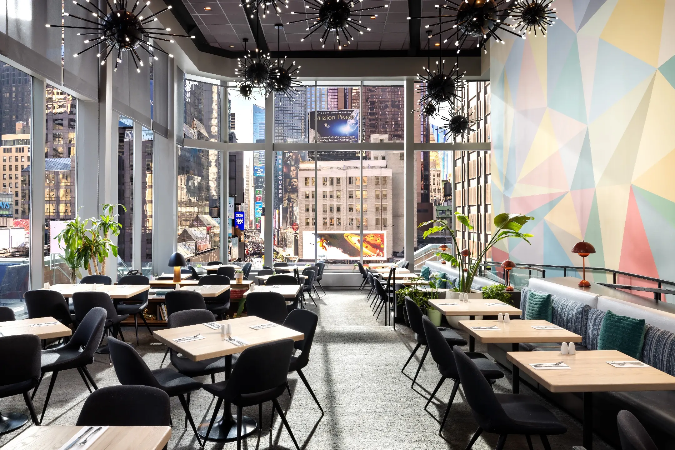 Modern restaurant interior with vibrant decor and large windows showcasing a bustling Times Square view.